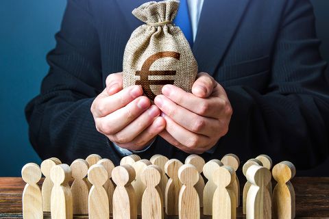 Mann mit Geldbeutel in den Hände und kleine Holzfiguren stehen davor