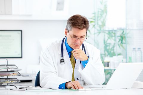 Arzt sitzt vor Laptop